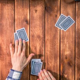 person shuffling cards on a wooden table